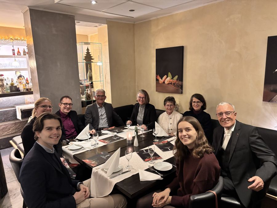9 people in an Italian Restaurant, smiling because of a marriage festivity.